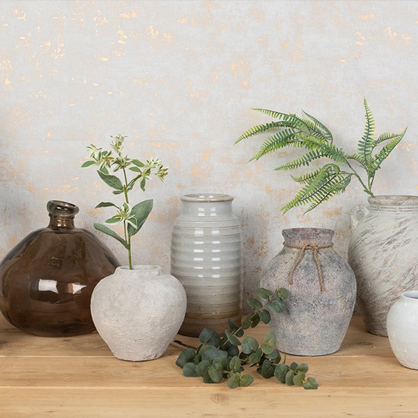 variety of ceramic and glass vases containing faux ferns and plants