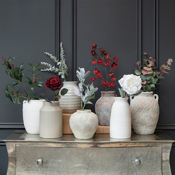 variety of ceramic and glass vases containing faux ferns and plants